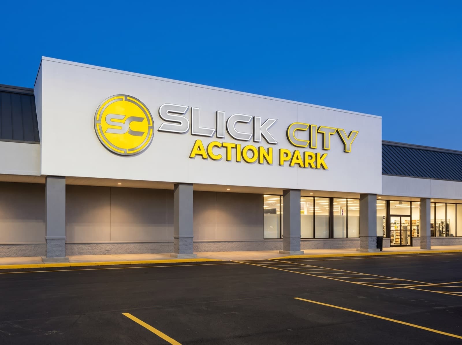 Large front-lit exterior sign for Slick City Action Park at dusk